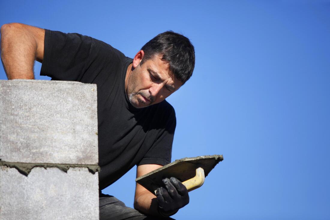 man putting wet cement on the concrete hallow blocks
