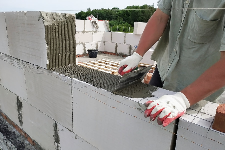 man putting wet cement to stick hallow blocks